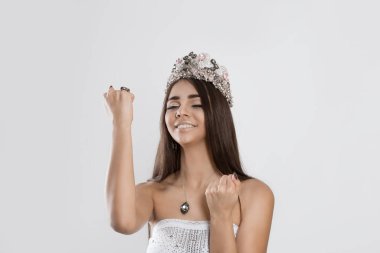 I am so Lucky I won the miss contest. Happy young woman happy girl exults pumping fists ecstatic isolated white grey background Celebrate success concept Beauty queen full matched makeup crystal crown