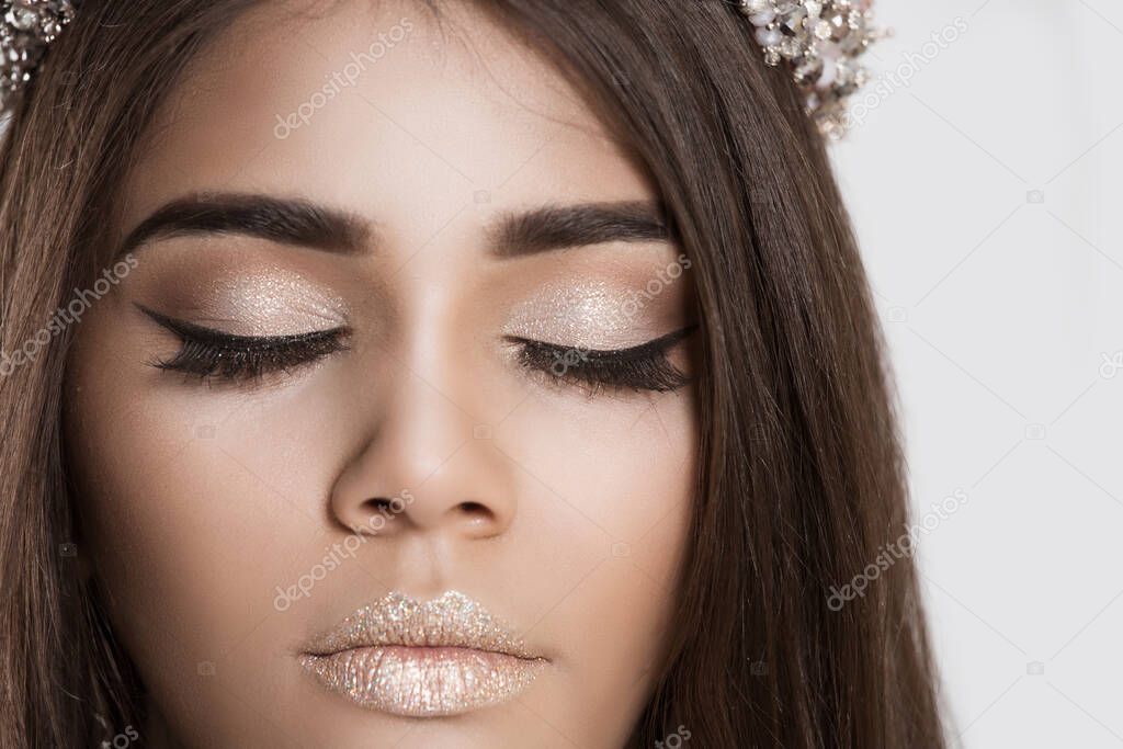 Trendy style makeup. Closeup portrait cropped image brunette woman face with beautiful shiny makeup eyes closed on white grey background wall. Dark skin beauty queen, thick eye brows, brown long hair