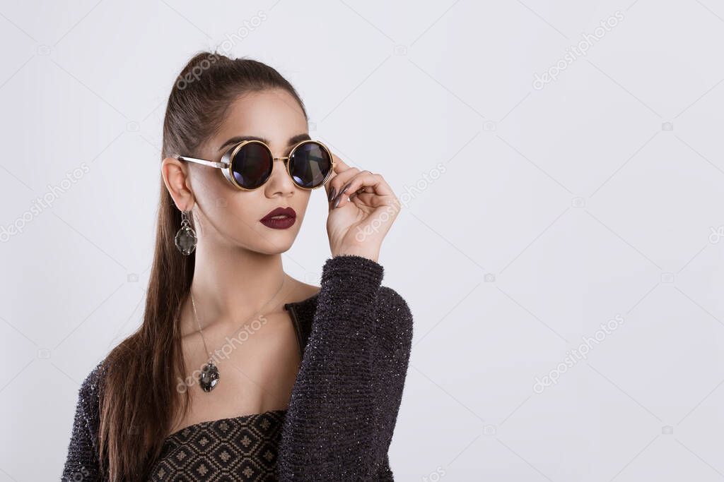 Closeup portrait confident successful beautiful attractive young woman fashion girl posing holding sunglasses hand on glasses isolated white grey background wall Positive human emotion face expression