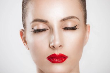 Çok güzel. Göz kamaştırıcı bir kadına yakın kırmızı dudaklar, siyah uzun kirpikleri temiz cilt gözleri beyaz arka plan duvarına izole edilmiş.