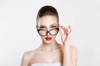 Portrait of beautiful skeptical woman in stylish cat eye eyeglasses, thinking and looking at you with disapproval. Holding her eye-wear glasses with her hand. Negative face expression, body language