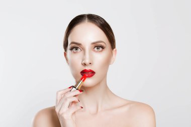 Dudaklarında kırmızı ruj kullanan güzel bir kadın izole edilmiş beyaz gri arka plan duvarı