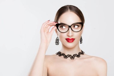 Attractive young woman in glasses girl looking to the right side copy space with her hand on eyeglasses young lady teacher business woman model smiling waggish holding her spectacles looking sidewards