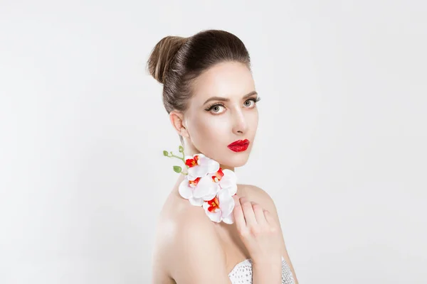 Hermosa chica con la celebración de flores de orquídea blanca aislado fondo blanco gris claro. Belleza Modelo Mujer Cara sonriente con labios rojos y uñas. Piel perfecta. Maquillaje profesional. Maquillaje. Arte de moda — Foto de Stock