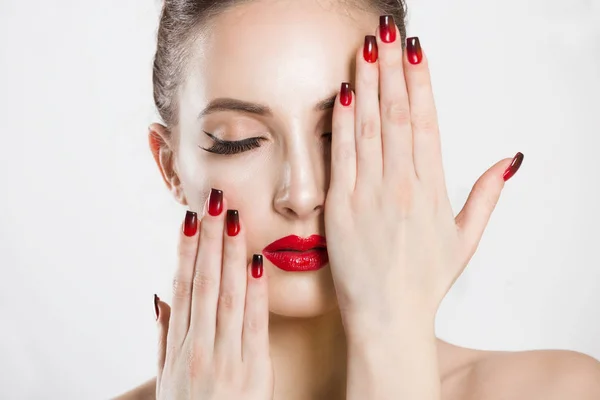 Red and black gradient nails and lips combination set. Beautiful young woman covering her eye with her hand, nude makeup false eyelashes, nails done, red lipstick — Stockfoto
