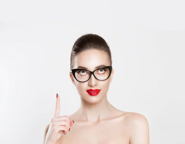 Mira aquí arriba. Primer plano morena mujer joven inteligente chica bastante sonriente en gafas para los ojos maquillaje desnudo labios rojos idea mirando hacia arriba señalando con el dedo en espacio de copia en blanco peinado vintage retro. Lenguaje corporal — Foto de Stock