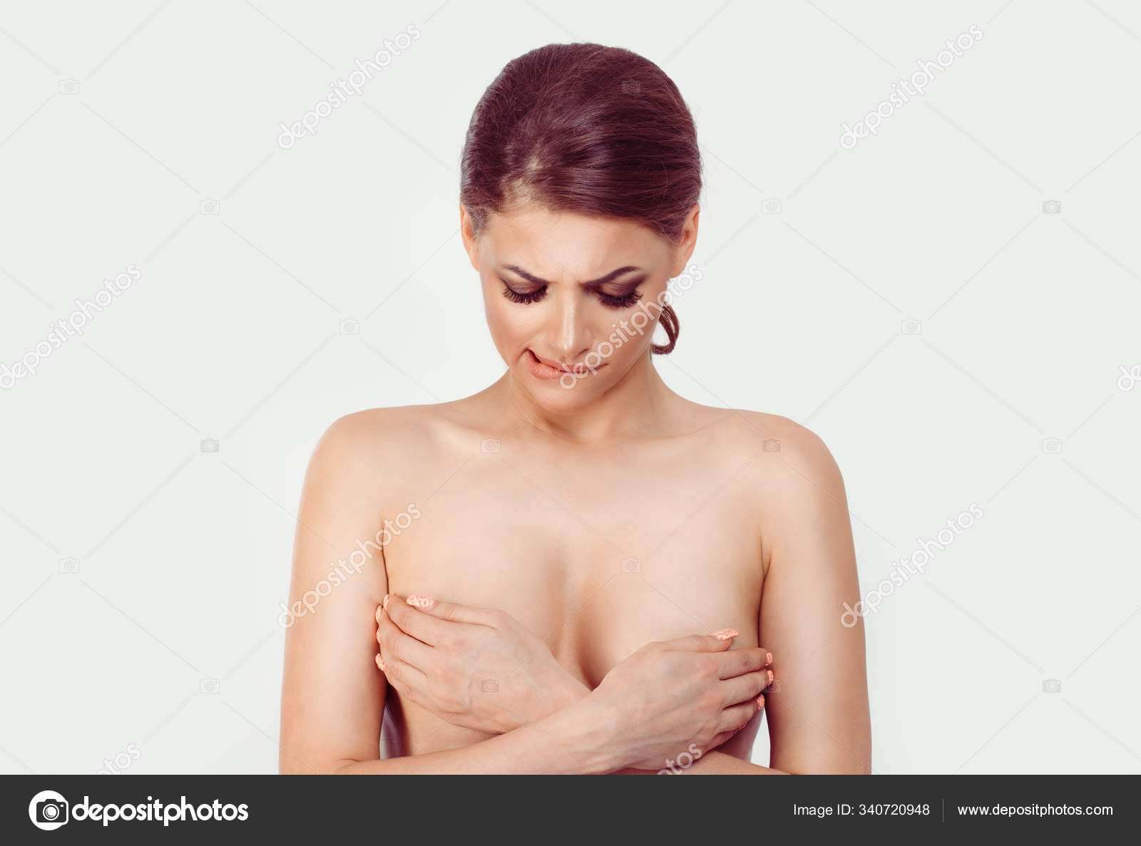 Brest cancer suspicion. Woman covers her breasts with her hands looking  doubtful skeptical at tits while passes medical check for breast cancer.  Isolated white background Stock Photo by ©HBRH 340720948