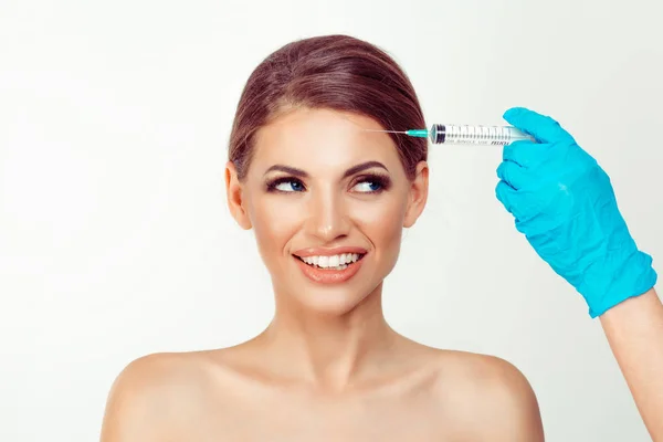 Mujer que recibe la inyección de toxina botulínica de ácido hialurónico en su frente en el consultorio médico mirando a la aguja lateral feliz sonrisa — Foto de Stock