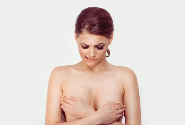 Brest cancer suspicion. Woman covers her breasts with her hands looking doubtful skeptical at tits while passes medical check for breast cancer. Isolated white background — Stock Photo, Image