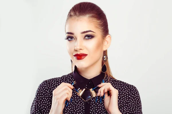 Stylish beauty. A brunette beautiful woman presents her jewels necklace, with thankful glad facial expression on white background. Fashion girl looking at camera red lips smokey eyes hair in ponytail — 스톡 사진