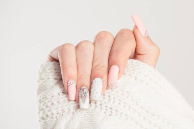 Tırnak cilası. Sanat manikürü. Modern stil mavi tırnak cilası. Pastel renkte pembe tırnaklar. Yün kumaş kollu bluz, izole edilmiş beyaz arka plan duvarı. Klasik gelin tırnak tasarımı.