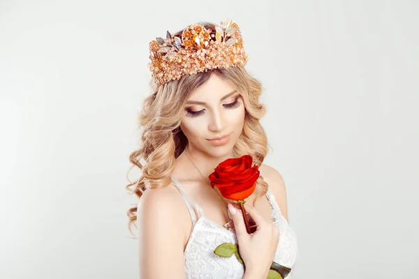 Beautiful like a flower. Closeup portrait blonde beauty curly girl with silver pink crown holding looking at red rose isolated white grey background wall — 스톡 사진