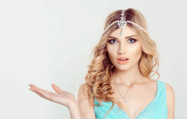 Beauty Queen bride woman with bright, tikka indian jewelry on head looking at you camera showing pointing to right copy space telling something light bridal makeup isolated grey white background wall — ストック写真