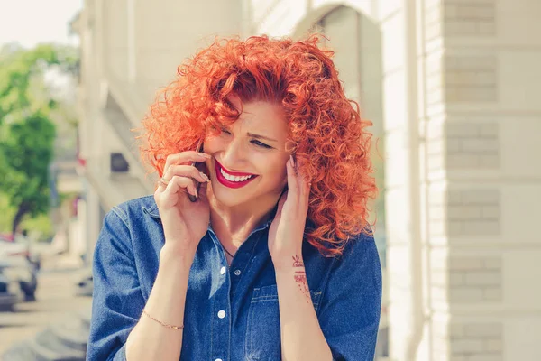 O quê? Não te estou a ouvir. Retrato irritado frustrado, mulher cabelo encaracolado vermelho falando no telefone móvel em pé fora com fundo da cidade. Sentimentos emocionais negativos . — Fotografia de Stock