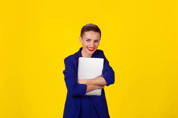 Feliz con el portátil. Retrato de estudiante universitario mirada feliz celebración tableta sonriendo. Multicultural chica Latina pelo corto labios rojos traje azul camisa amarilla aislado amarillo copia espacio fondo —  Fotos de Stock