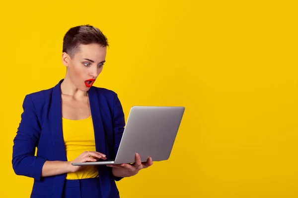 Sorprendido Shocked joven mujer de negocios pelo corto utilizando el ordenador portátil mirando la pantalla del ordenador impresionado en estupor sobre fondo amarillo. Expresión del rostro humano, emoción, sentimiento, lenguaje corporal, reacción — Foto de Stock