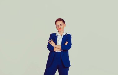 Genç profesyonel, yakın plan, kendine güveni olan güzel bir iş kadını, izole edilmiş açık yeşil ofis duvarı arka planı. Kısa saçlı, kırmızı dudaklı, mavi takım elbiseli, beyaz gömlekli.