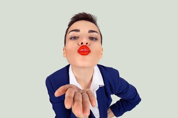 Closeup portrait of nerdy young funny distorted woman face with big red lips blowing sending  a kiss to you camera, isolated light green white background — 스톡 사진