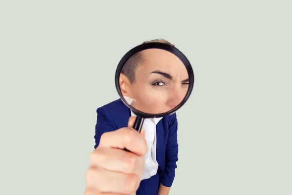 Meticulous detective curious business analyst. Closeup macro face curious girl looking through magnifying glass isolated light green white background