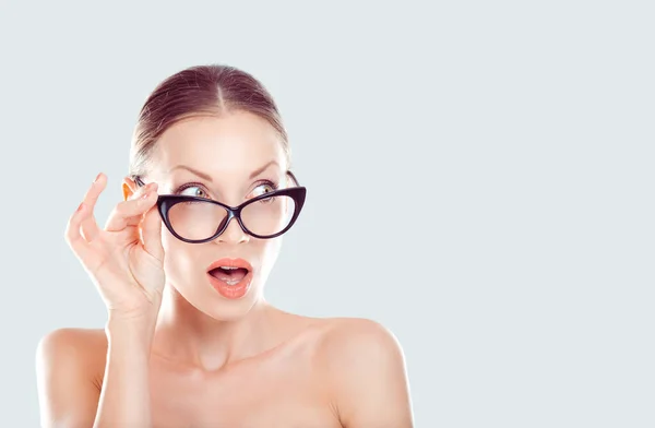 Mujer joven sorprendida con gafas fondo azul claro — Foto de Stock