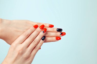 Tırnak cilası. Sanat manikürü. Modern stil kırmızı siyah oje ve üzerinde Eiffel üçgeni olan bir turne. Güzel eller şık renkli moda çiviler izole edilmiş açık mavi arkaplan