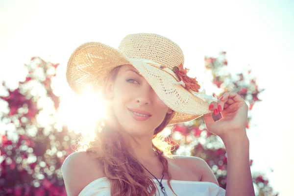 Dalgın, rahat bir kız, aşkın hasır şapkaya dokunduğunu, gün batımına bakarak yeşil çalılık çiçek arka planında izole edilmiş güneş ışınları şapkasını geçtiğini hayal ediyor. Retro tonlu, kırmızı filtre
