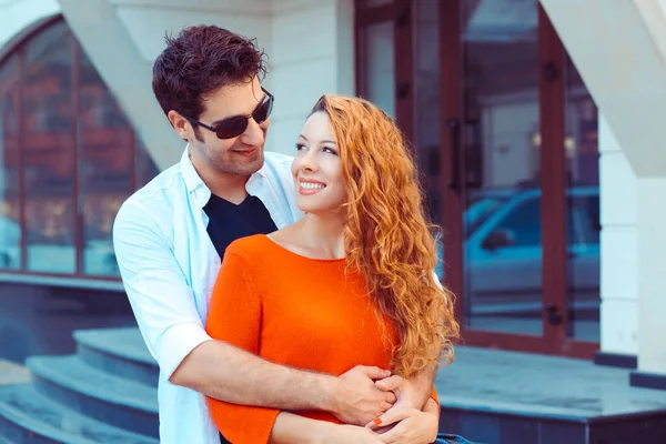 Felizes juntos. Romântico jovem casal hispânico sorrindo olhando uns para os outros abraçando de pé perto apartamento complexo cidade fundo — Fotografia de Stock
