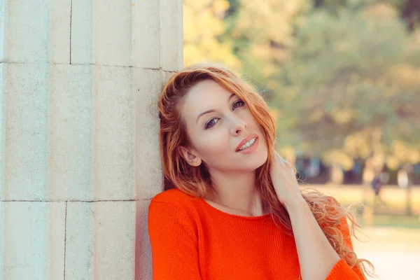 Joven hermosa mujer con el pelo largo y rojo. Chica tranquila con la piel limpia perfecta posando en el parque y mirando en la cámara — Foto de Stock