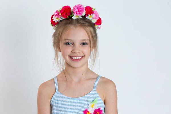 Cute kid girl smiling looking at you camera happy posing. Closeup portrait of Caucasian kid model with floral headband isolated on white grey gray copy space background. Horizontal image.