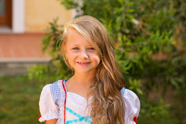 Feliz niña sonriendo a la cámara en un día soleado arbustos verdes aislados jardín natural cerca de la casa al aire libre en el fondo — Foto de Stock