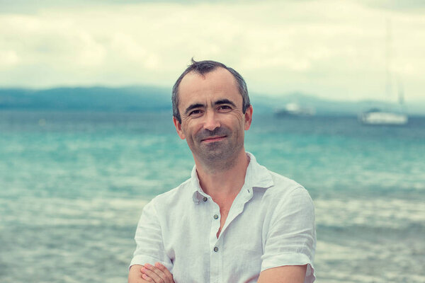 Middle aged man smiling no teeth by the beach in summer