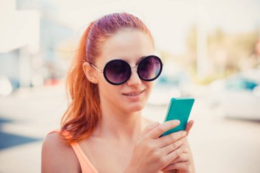 Genç kadın bir şehir sokakta yürürken cep telefonu ile beyaz gömlek meşgul