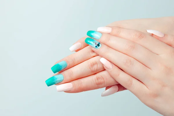 Art manicure. Trendy nail polish. Beautiful stylish woman hands with green white gradient pink pastel colors manicure with crystal gems isolated light blue background. — Stock Photo, Image