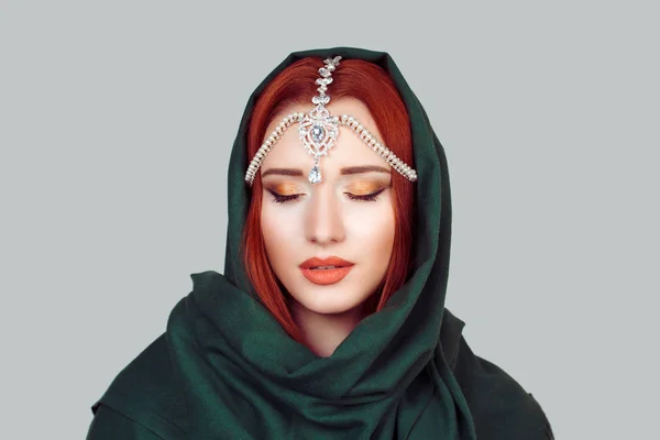 Κοντινό πλάνο του προσώπου μιας όμορφης γυναίκας με μάτια κλειστά με πράσινο μαντήλι χιτζάμπ και ανατολίτικα κοσμήματα στο κεφάλι απομονωμένα σε ανοιχτό γκρι φόντο. Σκέψη τόσο βαθιά με κλειστά μάτια — Φωτογραφία Αρχείου