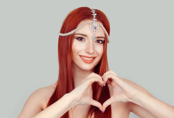 Love and care. Pretty romantic young redhead woman making a heart gesture with her fingers, showing her love and affection with a happy tender smile isolated light green gray background — 스톡 사진