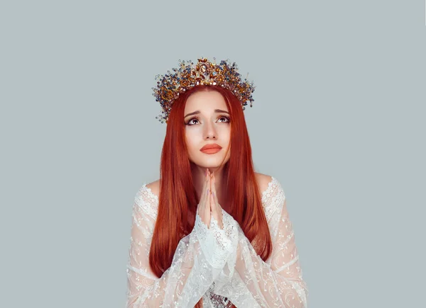 Beauty queen praying. Young woman praying looking up with hope pretty woman with crystal crown on head isolated on light gray background wall. face expression human emotion