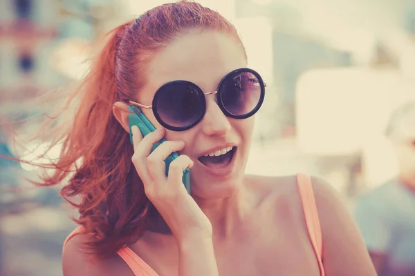 Έκπληκτο κορίτσι μιλάει στο κινητό τηλέφωνο ανοιχτό στόμα, κόκκινο κεφάλι — Φωτογραφία Αρχείου