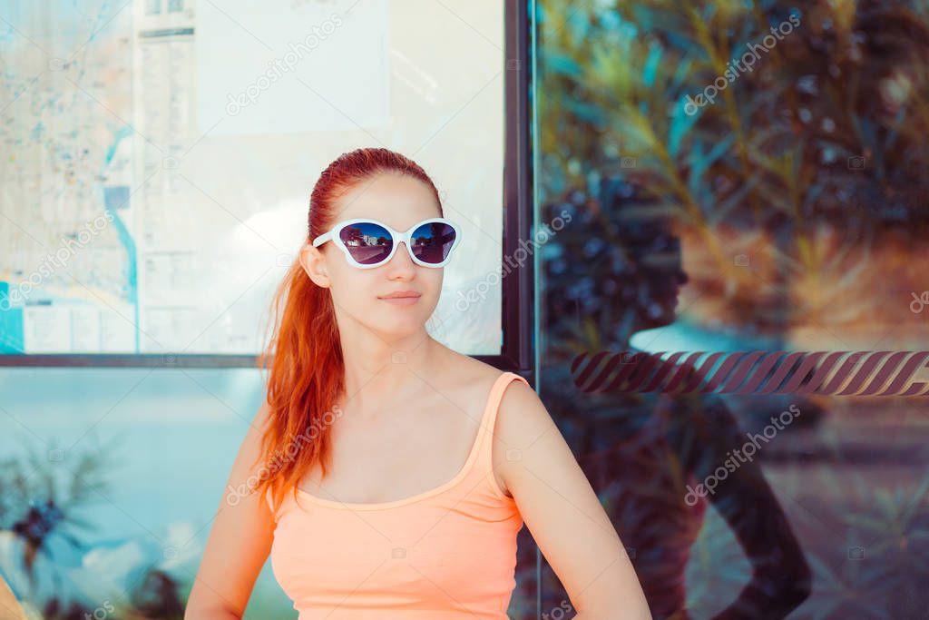 The young redhead woman stands on the bus stop she expects the bus