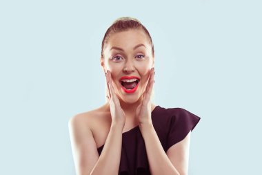 Şok oldum. Yakın plan mutlu genç kadın, kopyalama alanını arıyor. İnançsız ellerle, yanaklardan uzak, açık mavi arka plan, pozitif, insani duygu ifadesi tepkisi.