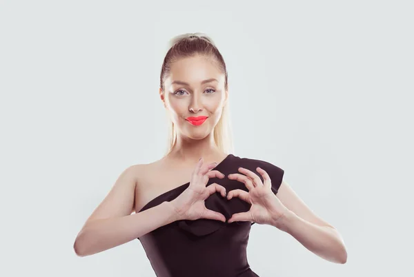 Love. Closeup portrait slight smile happy young woman with pink lips making heart sign, symbol with hands isolated white light wall background. Positive human emotion expression feeling body language — 스톡 사진