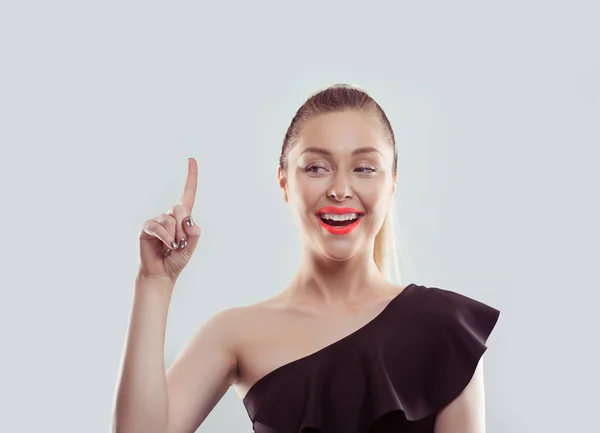 Retrato feliz bela mulher animada apontando com o dedo para cima isolado no fundo da parede cinza claro branco. Expressões faciais humanas positivas, emoções, sentimentos linguagem corporal, percepção — Fotografia de Stock