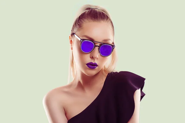 Mira mi estilo, soy todo violeta púrpura. Mujer muestra gafas de sol espejadas violetas en conjunto combinación con lápiz labial, pelo rubio oscuro ombre aislado sobre fondo blanco verde claro con espacio para copiar — Foto de Stock