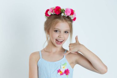 Sevimli kız bana el işareti işareti yap diyor. Beyaz gri arka planda izole edilmiş çiçek tokalı beyaz çocuk modeli yakın plan portresi. Yatay resim.