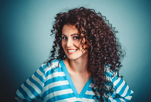 Happy curly woman brunette smiling at you camera on blue background.