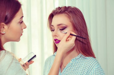 Profesyonel makyöz güzel bir genç kızla çalışıyor..