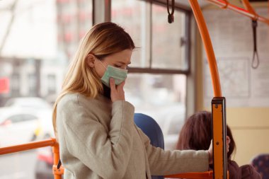 Hasta kız, ameliyat maskesi takan sarışın genç bir kadın toplu taşıma otobüsüyle seyahat ediyor kendini kötü hissediyor, hasta, Coronavirus tarafından vuruluyor, Covid2019.