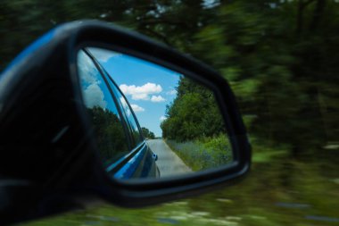 Ormanda ya da kırsal kesimde virajlı bir yolun dikiz aynasından yansıması. Dramatik manzara