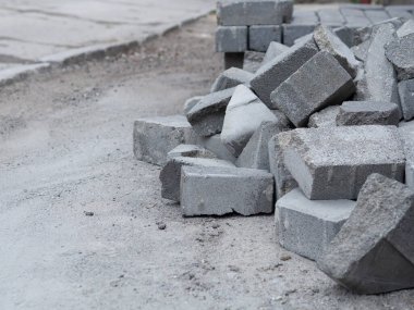 Şehrin sokaklarında taş döşeme yığını, kaldırım konseptini yeniden inşa etmek, arka planda asfalt yol.