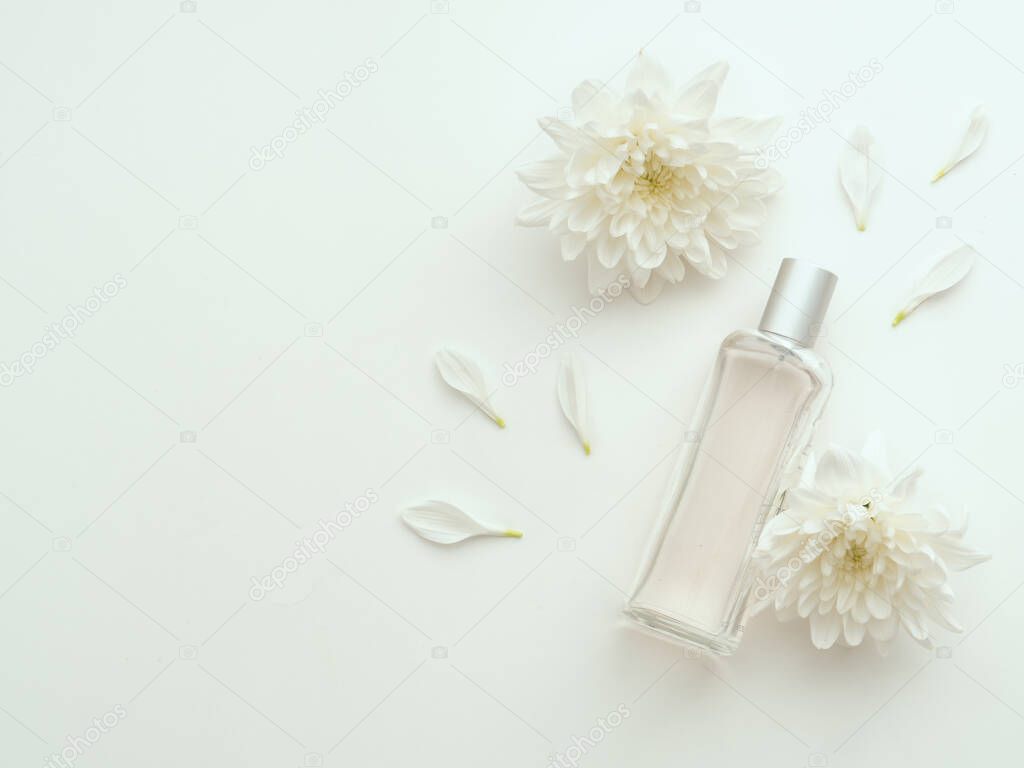 Perfume bottle with floral aroma. Cosmetics packaging design concept or mock-up with blank transparent bottle with liquid soap, shower gel on white surface surrounded by delicate peony petals