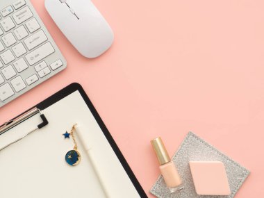 Klavye faresi, kalem makyaj aletleri olan pano, pembe şeftali rengi arka planda izole edilmiş kozmetik ürünler, fotokopi alanı. Düz konum, üst görünüm kopyalama alanı. Kadınsı güzellik blogcusu iş yeri kavramı